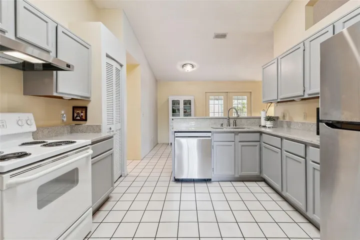Kitchen features tile flooring and grey cabinetry