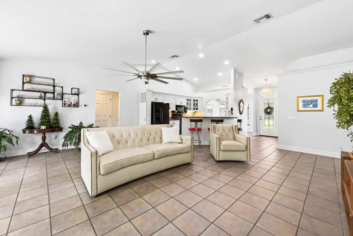 A spacious Family Room impresses with soaring vaulted ceilings, a STYLISH SLINGER CEILING FAN (2021), and a beautiful MASONRY WOOD-BURNING FIREPLACE.