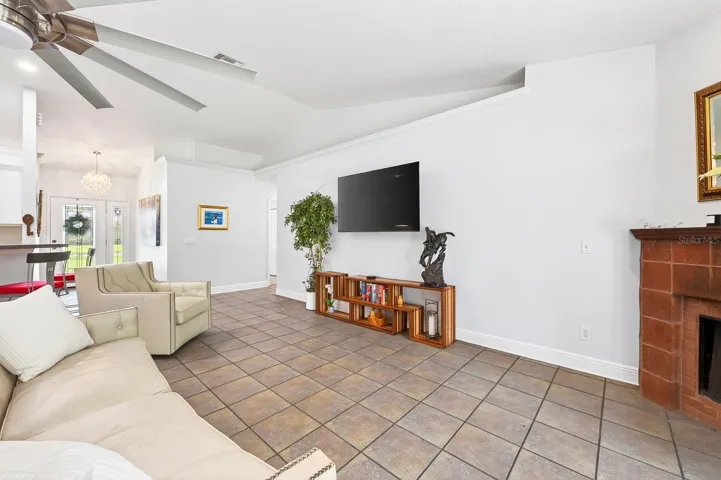 A spacious Family Room impresses with soaring vaulted ceilings, a STYLISH SLINGER CEILING FAN (2021), and a beautiful MASONRY WOOD-BURNING FIREPLACE.