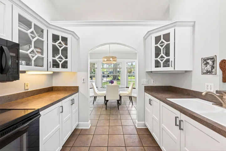 The Kitchen showcases BEAUTIFULLY UPDATED SOLID WOOD WHITE CABINETRY, including select glass-front display cabinets.