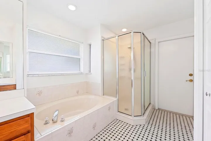 An ELEGANT EN SUITE BATH in the Primary Suite features dual vanities, beautiful tile flooring, a garden tub, and separate step-in shower.