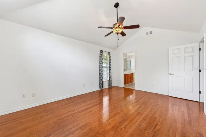 The Primary Suite is thoughtfully positioned apart from the secondary bedrooms, creating a PEACEFUL PRIVATE RETREAT complete with CATHEDRAL  CEILINGS, hardwood flooring, a walk-in closet, and an ELEGANT EN SUITE BATH.