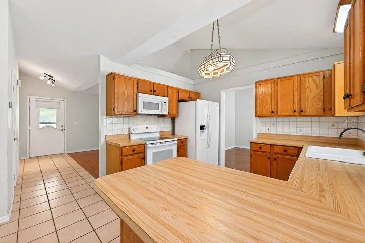 The open Kitchen provides plenty of solid wood cabinets, beautiful butcher block countertops and a stylish tile backsplash.