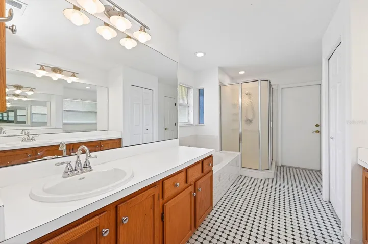 An ELEGANT EN SUITE BATH in the Primary Suite features dual vanities, beautiful tile flooring, a garden tub, and separate step-in shower.