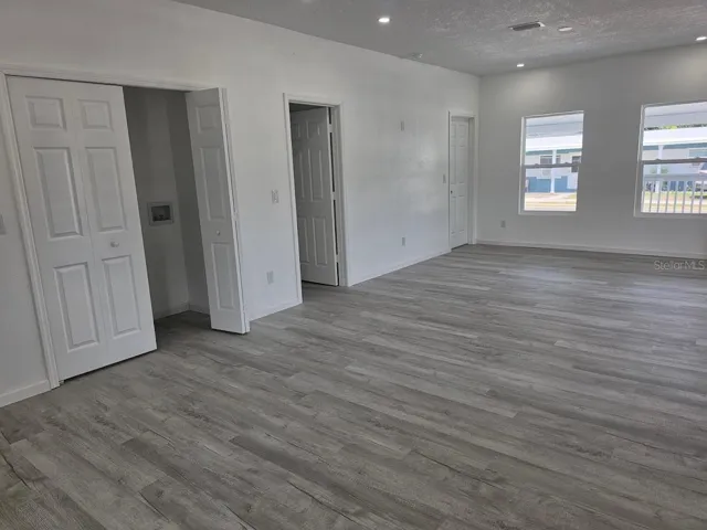 Bright open-concept living area with recessed lighting, premium laminate flooring, abundant natural light, and a convenient interior laundry closet.