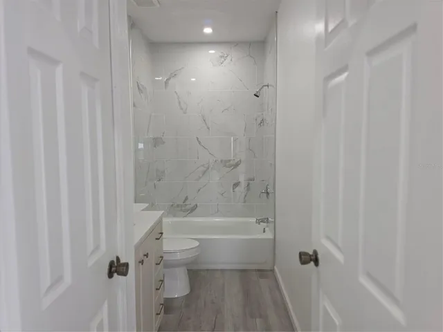 Bathroom featuring a tub/shower combination and an additional interior closet for extra storage and convenience.