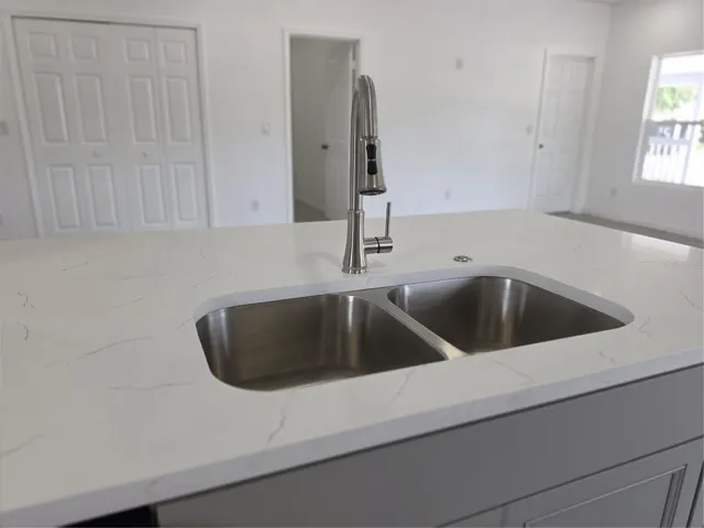 Spacious granite kitchen island countertops, a double-basin sink, sleek pull-down faucet, and a convenient garbage disposal button for added functionality and style.