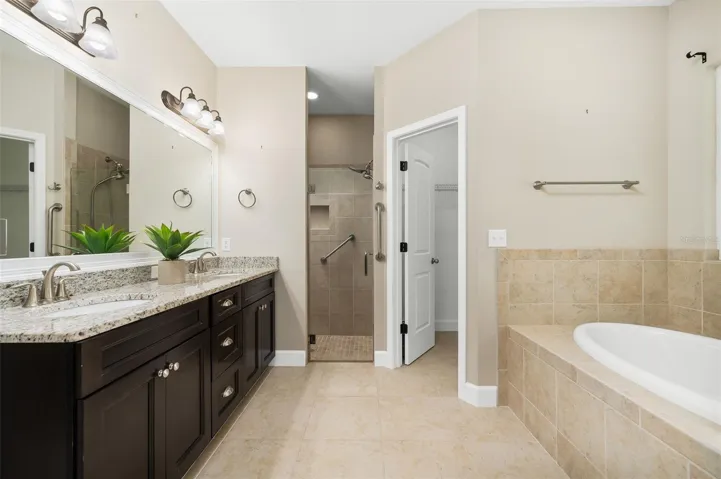 Large primary bathroom with dual vanity, soaking tub, walk-in shower and 2 walk-in closets
