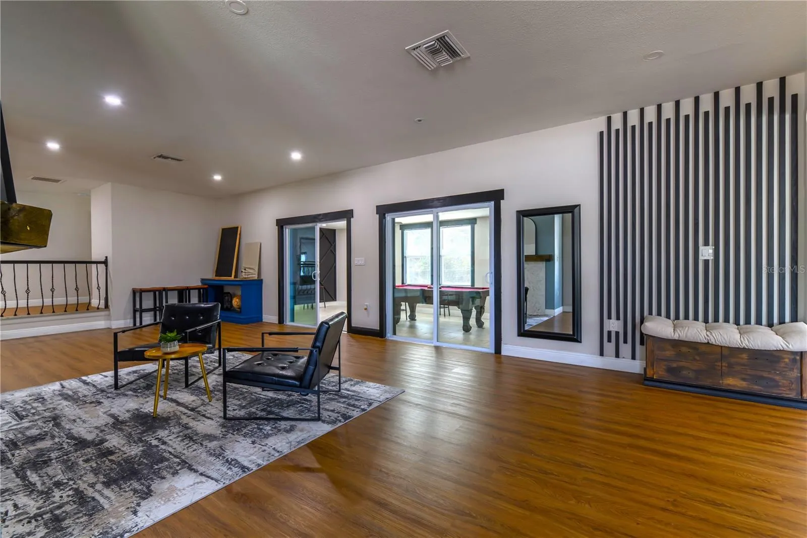 Left to Right:  (2) Step Up Hallway leading to Bedroom 2 & 3, Living Room/Fireplace sitting area, 2 sets of Sliding Glass Doors leading into the Florida Room with AC and Wall Mounted Wood Slat Accents