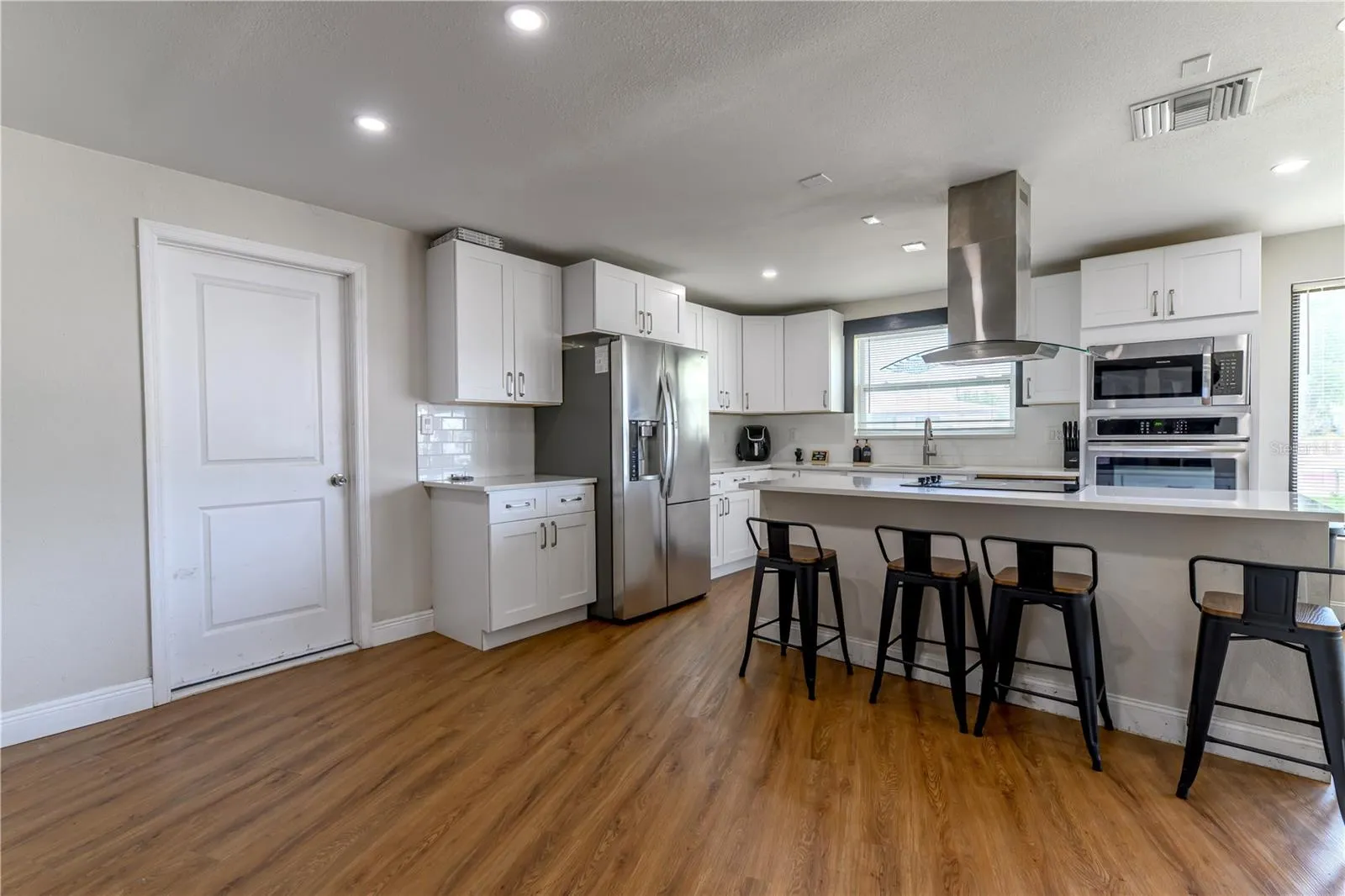 Interior Garage Door Entry into Open Kitchen Concept with Stainless Steel Appliances