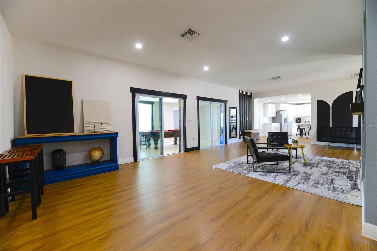 Left to Right:  (2) Step Down into Open Living Area with Wood Slat Wall Accents, Florida Room Entry with 2 sets of Double Sliding Glass Doors into the Kitchen Area & Garage Exit Door (Interior)