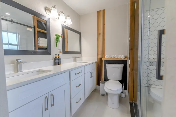 Primary Ensuite Bathroom with Dual Sinks and Wood Slat Wall Accents and Shelving