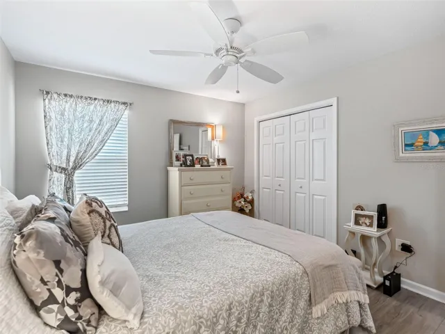 Bright and inviting second bedroom featuring durable vinyl flooring, a ceiling fan, and plenty of natural light.