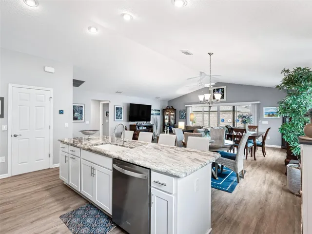 Bright, open floor plan with vaulted cathedral ceilings, vinyl flooring, and abundant natural light.