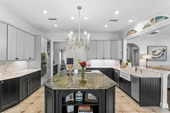 The kitchen features a large island with exotic granite, quartz countertops, warming drawer, wine refrigerator, abundant prep space, and a large walk-in pantry.