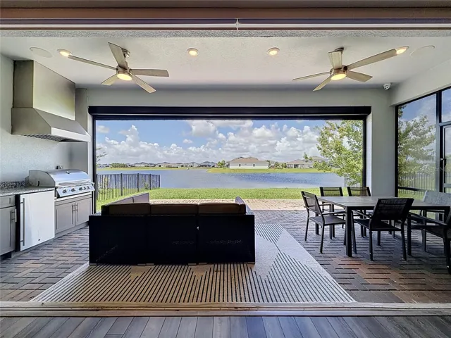 Covered lakefront lanai with a summer kitchen and fully retractable glass sliding doors for seamless indoor-outdoor living