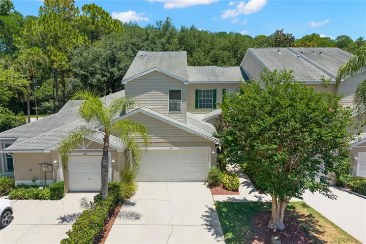 3-bedroom, 2.5-bath, two-story townhouse with a covered entry, neutral exterior palette, mature landscaping, and a two-car garage with an extended driveway for additional parking. Located within the East Lake Landings community with sidewalks, maintained grounds, and a low-maintenance homesite.