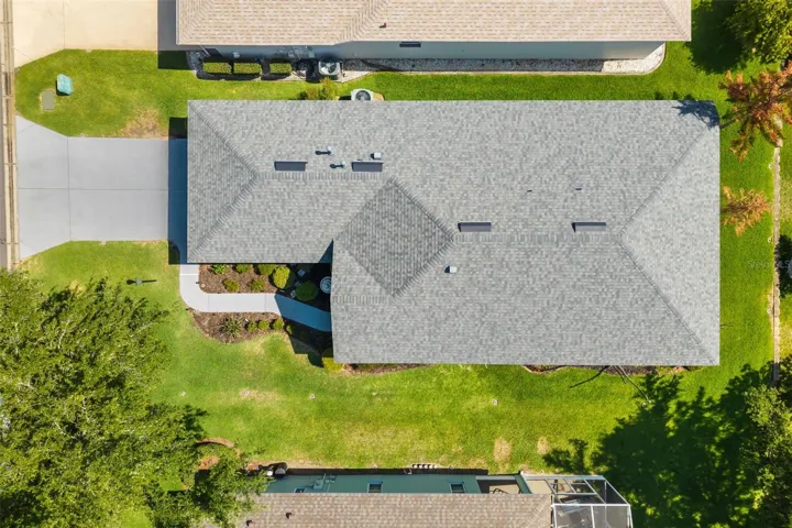 Bird's-eye view of the property showcasing the home's footprint, lot, and surrounding green space.