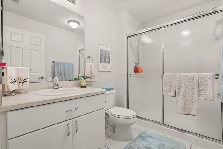 Guest bathroom featuring a large vanity, generous storage, and an easy-to-maintain walk-in shower.