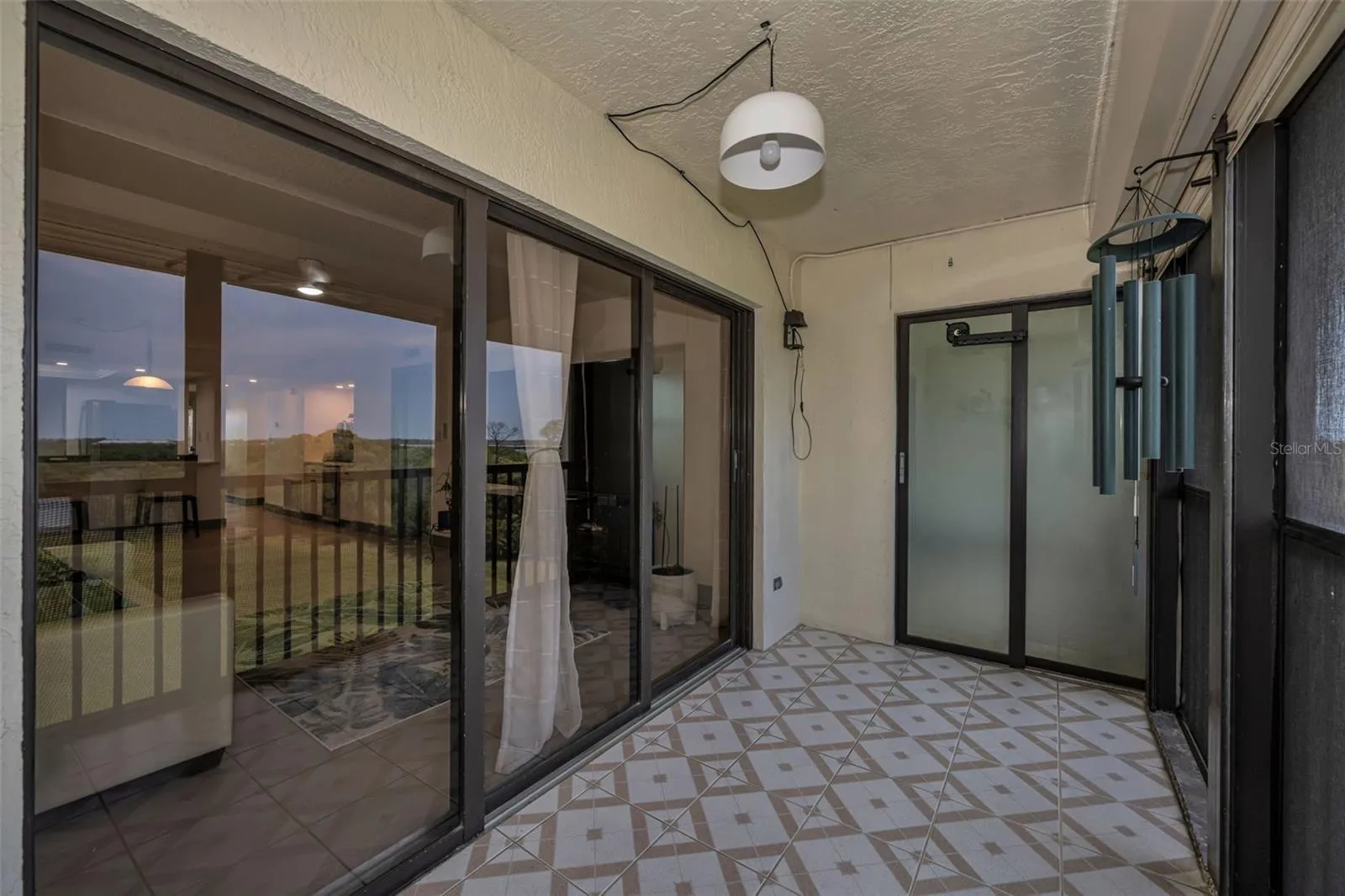 Balcony with sliding glass doors to living room and bedroom.  Screened in and shutters for protection.