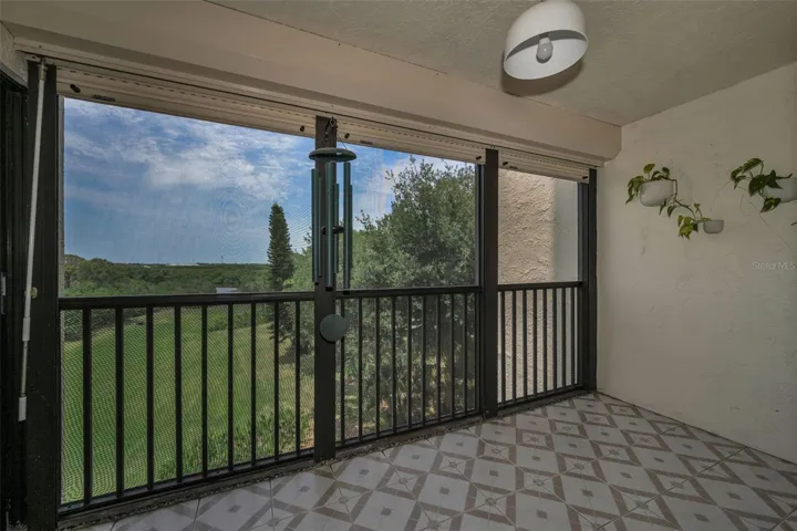 Rear, screened balcony overlooking plush landscaping and more. Beautifully tiled!
