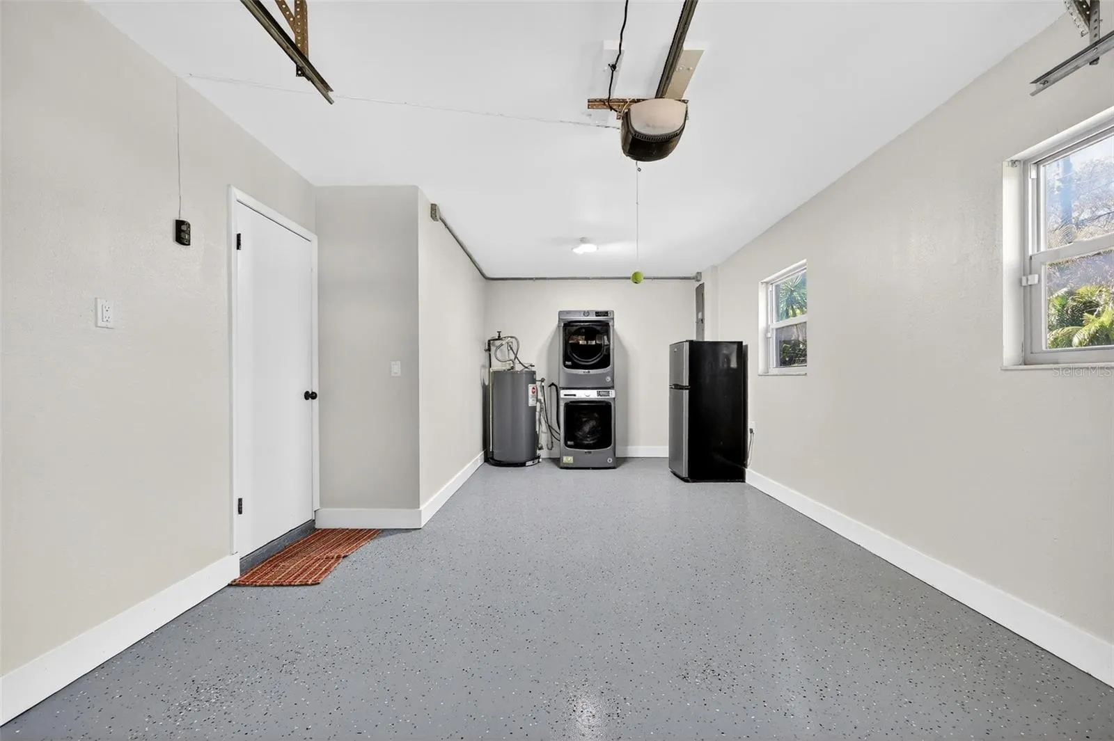 Single garage with garage door opened. Fresh epoxy flooring.  Garage stacked washer and dryer.