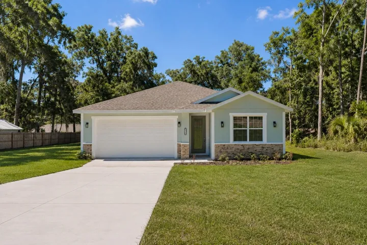 Front exterior view of the home featuring a spacious driveway, two-car garage, and oversized lot.