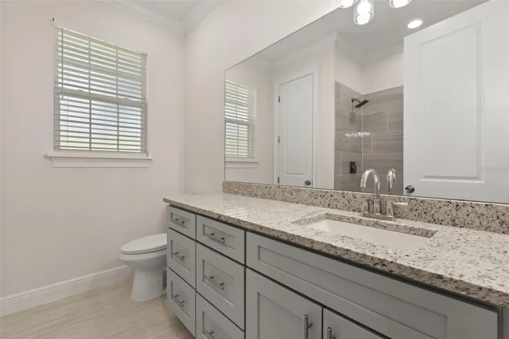 Guest bathroom featuring dual sinks, granite countertops, and updated finishes.