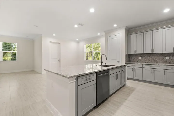 Modern kitchen featuring granite countertops, oversized island, and stainless steel appliances.