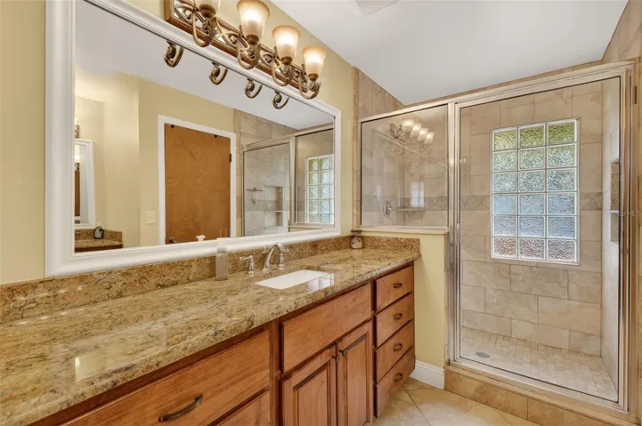Primary bathroom with granite, dual sinks, tiled shower