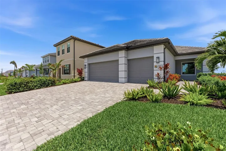 Paver driveway panning to right side of house with landscape plantings