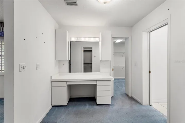 Functional dressing room featuring a built-in vanity, abundant storage, and direct access to the primary bath and walk-in closet
