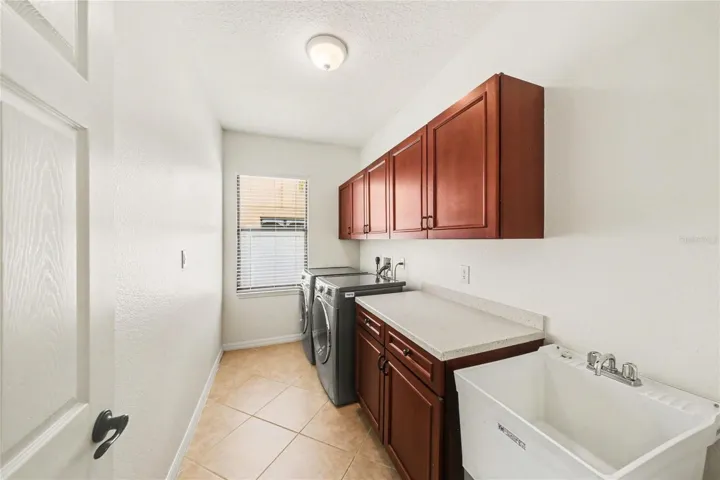 Inside laundry room with cabinetry and splash sink
