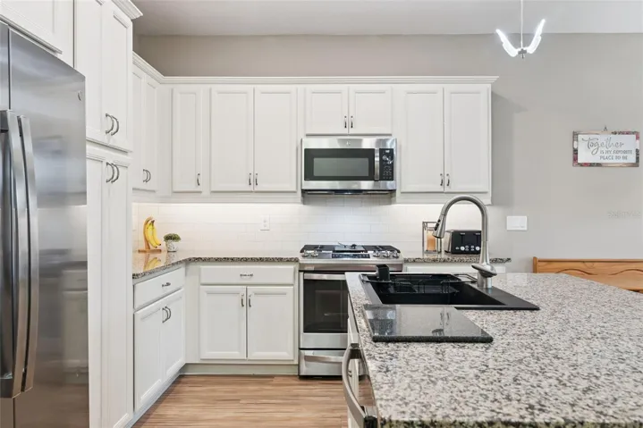 Spacious kitchen boosts upgraded granite counters, soft close cabinets with under cabinet lighting, subway tile backsplash and gas range with true exhaust hood (NOT a re-circulating fan).