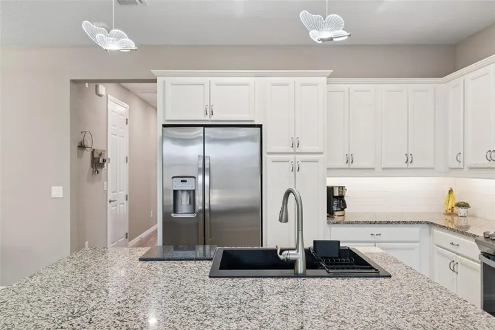 Looking from kitchen to entry hall. Garage entry can be seen to left down the hall. A new deep composite sink replaced the builders grade stainless for durability and ease.