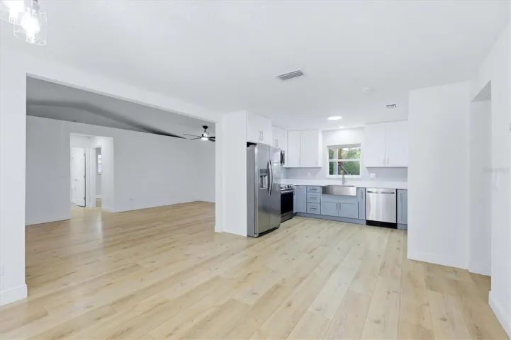 View from dining are into kitchen and living area.  Kitchen features modern cabinetry in two tones plus a farm style sink