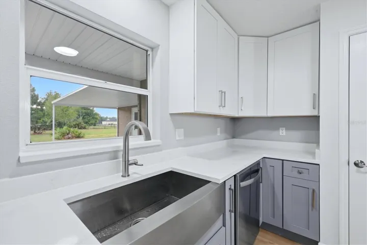 Deep stainless-steel farm style sink with Delta faucet featuring a virtually un-noticeable pull-out nozzle with sprayer