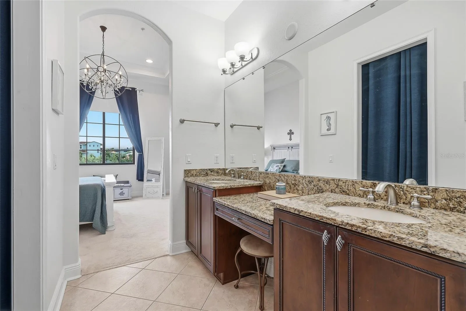 Primary bathroom with granite counters and dual vanity.
