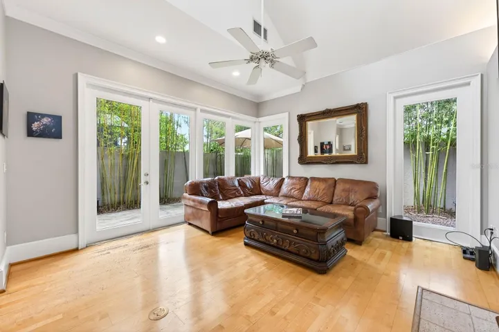 The Living Room is both inviting and dramatic, featuring a GAS FIREPLACE, oversized windows that flood the space with natural light, and French doors that open to the private outdoor patio and backyard retreat.