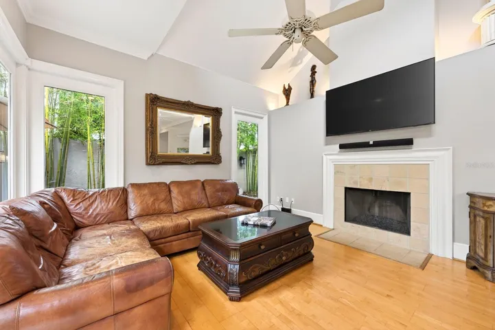The Living Room is both inviting and dramatic, featuring a GAS FIREPLACE, oversized windows that flood the space with natural light, and French doors that open to the private outdoor patio and backyard retreat.