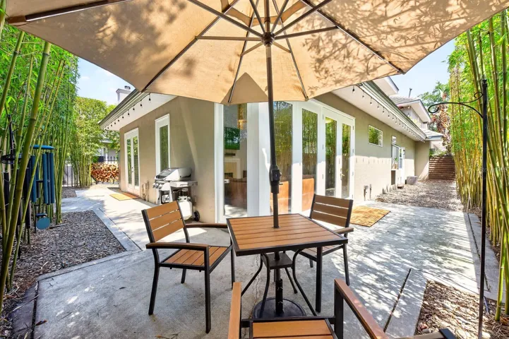 The yard is enclosed by a BLACK IRON FENCE with GATED ENTRY, while MATURE BAMBOO lining the perimeter provides shade, privacy, and a tranquil ambiance rarely found in townhome living.