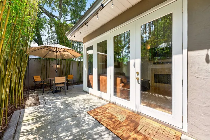 The yard is enclosed by a BLACK IRON FENCE with GATED ENTRY, while MATURE BAMBOO lining the perimeter provides shade, privacy, and a tranquil ambiance rarely found in townhome living.