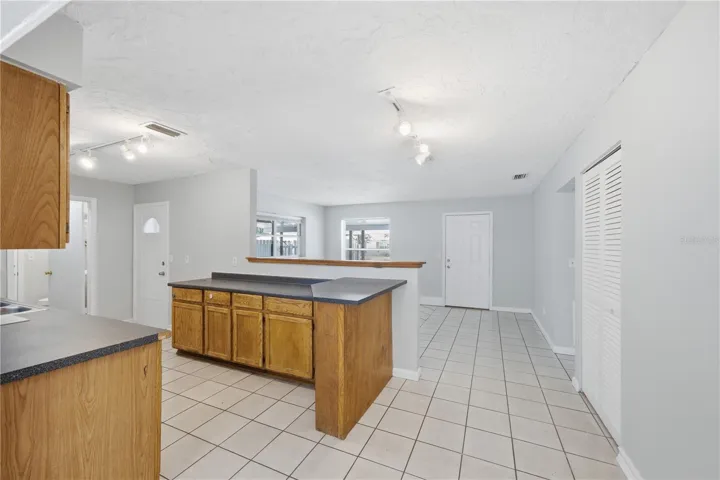 This photo showcases the view from the kitchen, offering a clear perspective into the inviting living room space and the entryway featuring the front door. The listing also includes a versatile bifold closet, adaptable for use either as a convenient coat closet or a practical pantry, providing functional storage solutions.