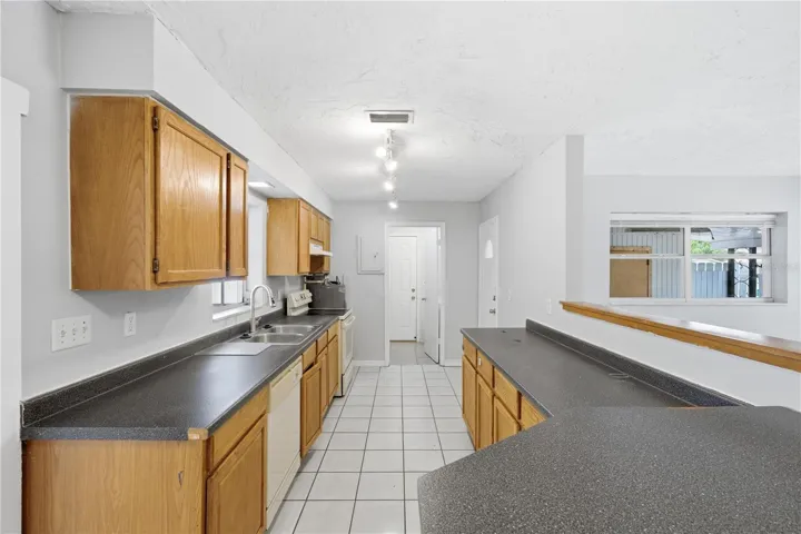 This gourmet kitchen boasts an inviting open floor plan connecting to the living area, offering picturesque views of the front sink, screened patio, and secure, fenced backyard.