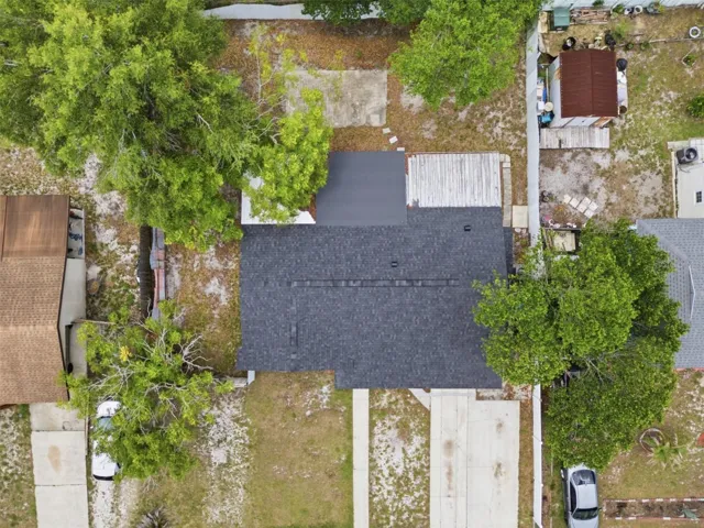 Aerial view of property showing driveway, front walkway and concrete pad in backyard