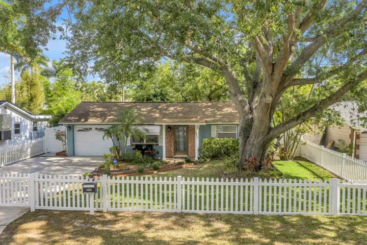 Framed by a classic white picket fence, this inviting front yard offers privacy, charm, and timeless appeal