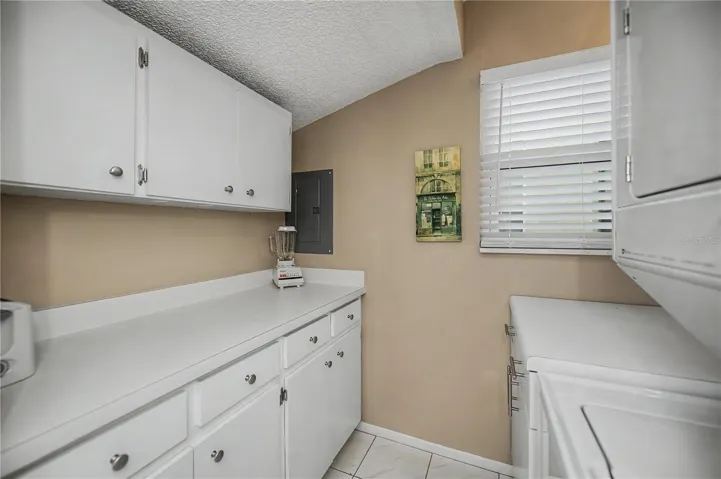 Great laundry room with stackable unit and plenty of cabinet space.