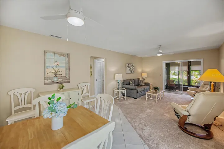 An overall view of the great room including dining area and the living room.  Set of patio doors opens onto the lanai.