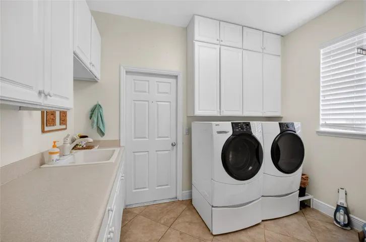 First flr laundry room. Washer and dryer remain. Built in white cabinets for storage.
