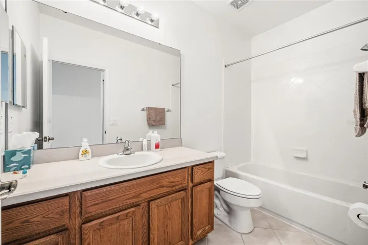 Guest bath has honey oak cabinetry and ample counter space with large tub